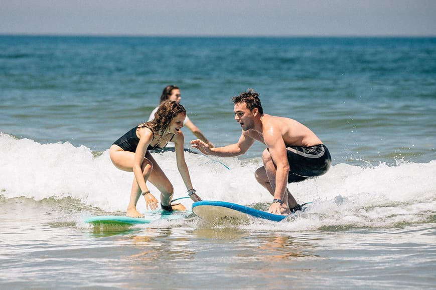 Beginner surfer receiving help during a surf lesson in France