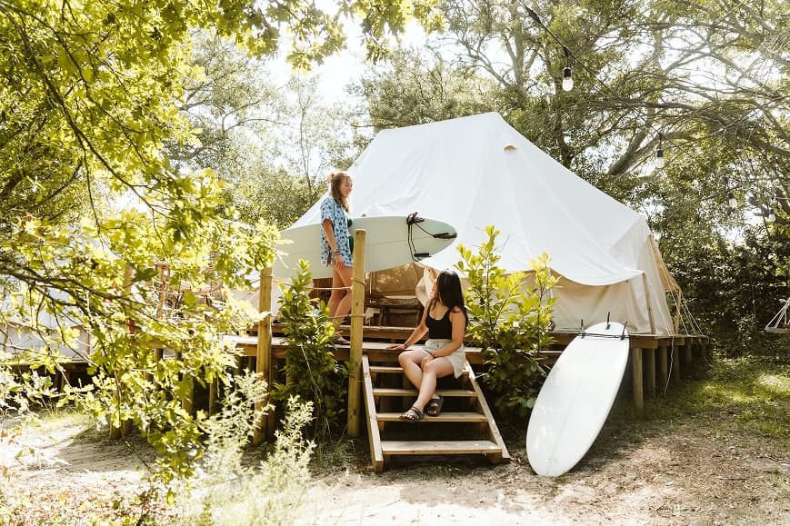 Guests with surfboards outside a glamping tent at Dreamsea France Soulac-sur-Mer