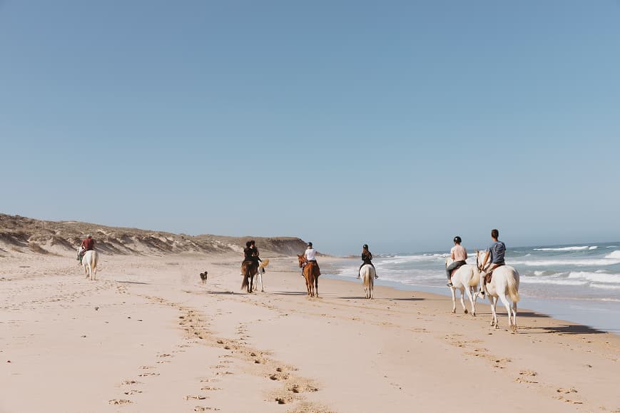 Guests riding horses along the beach on the Alentejo coast