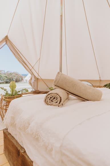 Bed inside a Dreamsea Portugal Alentejo glamping tent with towels and natural decor