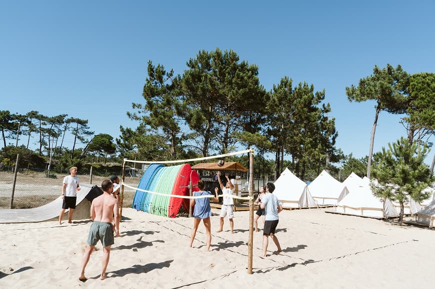 Guests playing beach volleyball beside surfboards and glamping tents at Dreamsea Portugal Centro