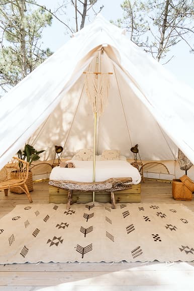Bright interior of a white glamping tent at Dreamsea Portugal Centro with double bed and boho decor