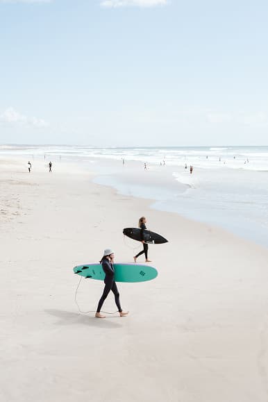 Two surfers walking along Praia da Tocha with surfboards