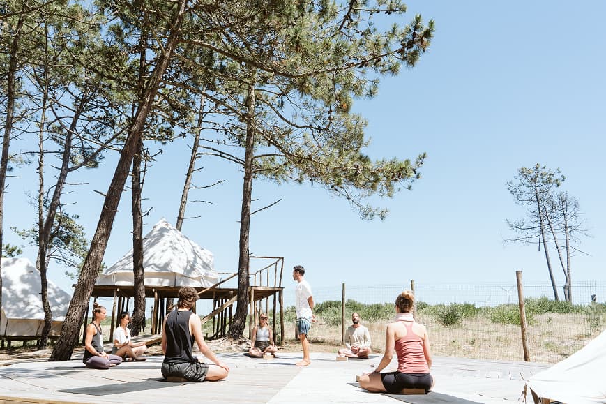 Group yoga class on the outdoor deck surrounded by pine trees at Dreamsea Portugal Centro