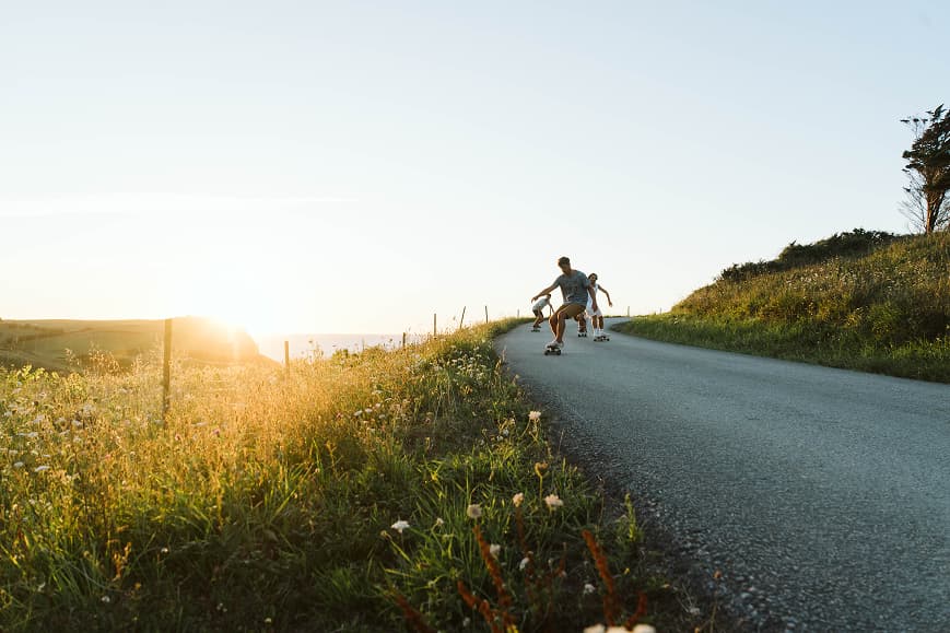 Huéspedes practicando skate al atardecer por una carretera costera de Cantabria