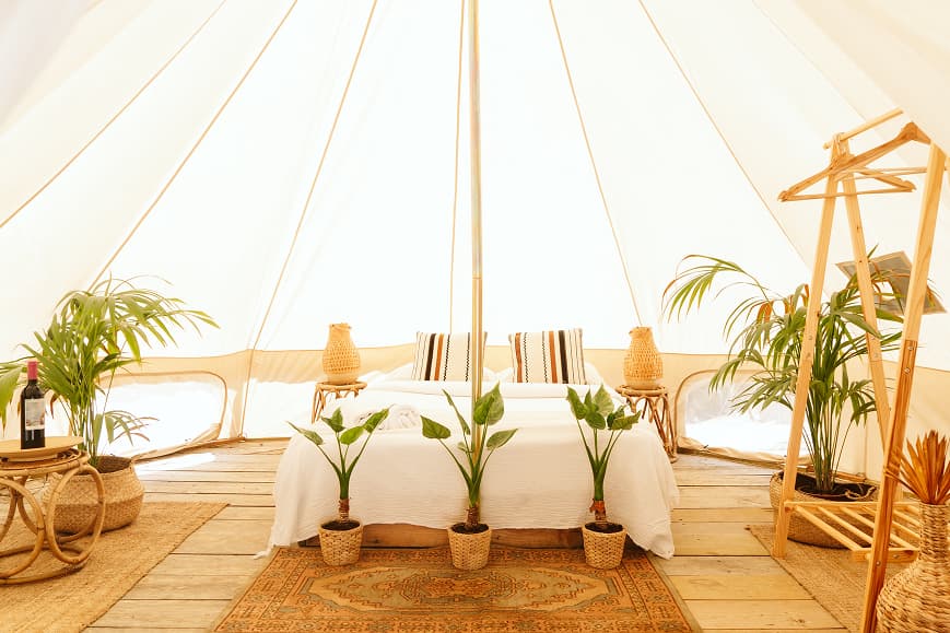 Luminoso interior de tienda glamping en Dreamsea Cantabria con cama doble, plantas y decoración bohemia