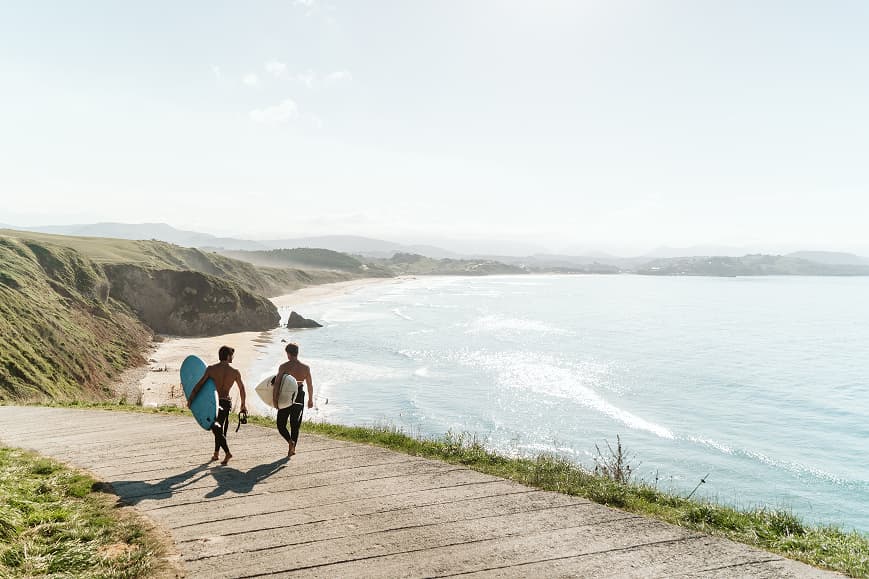 Dos surfistas caminando con sus tablas sobre la costa de Cantabria