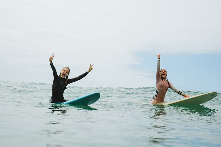 Dos surfistas sentados sobre sus tablas celebrando en el agua en Cantabria