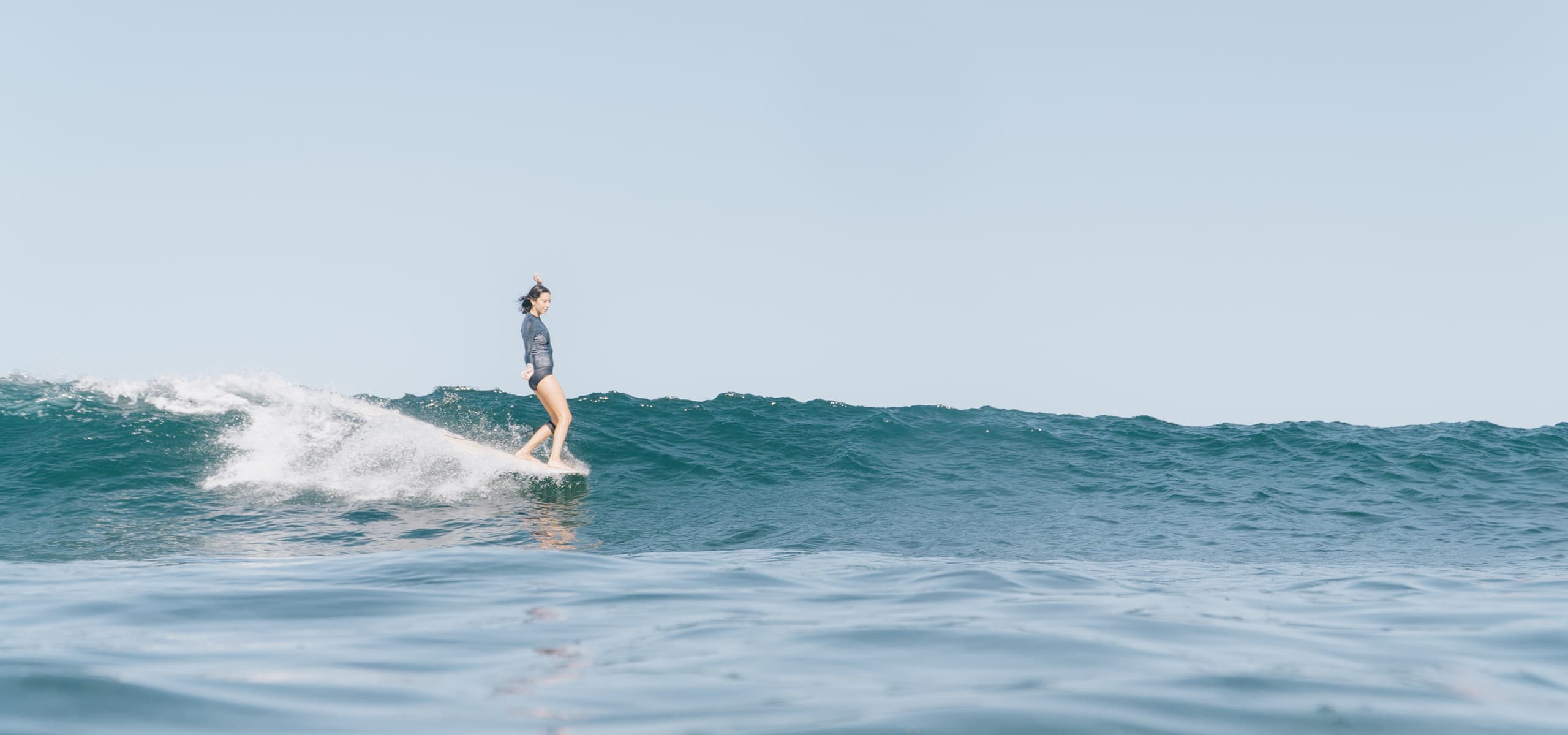 Surfer riding a small wave in the ocean in Gran Canaria, Canary Islands, Spain