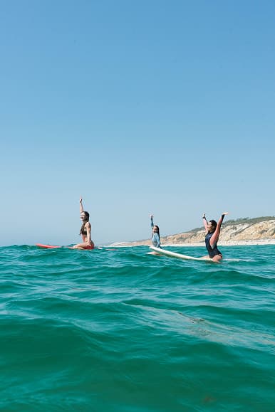 Surfers sitting on boards in clear Atlantic water during a surf session in Alentejo