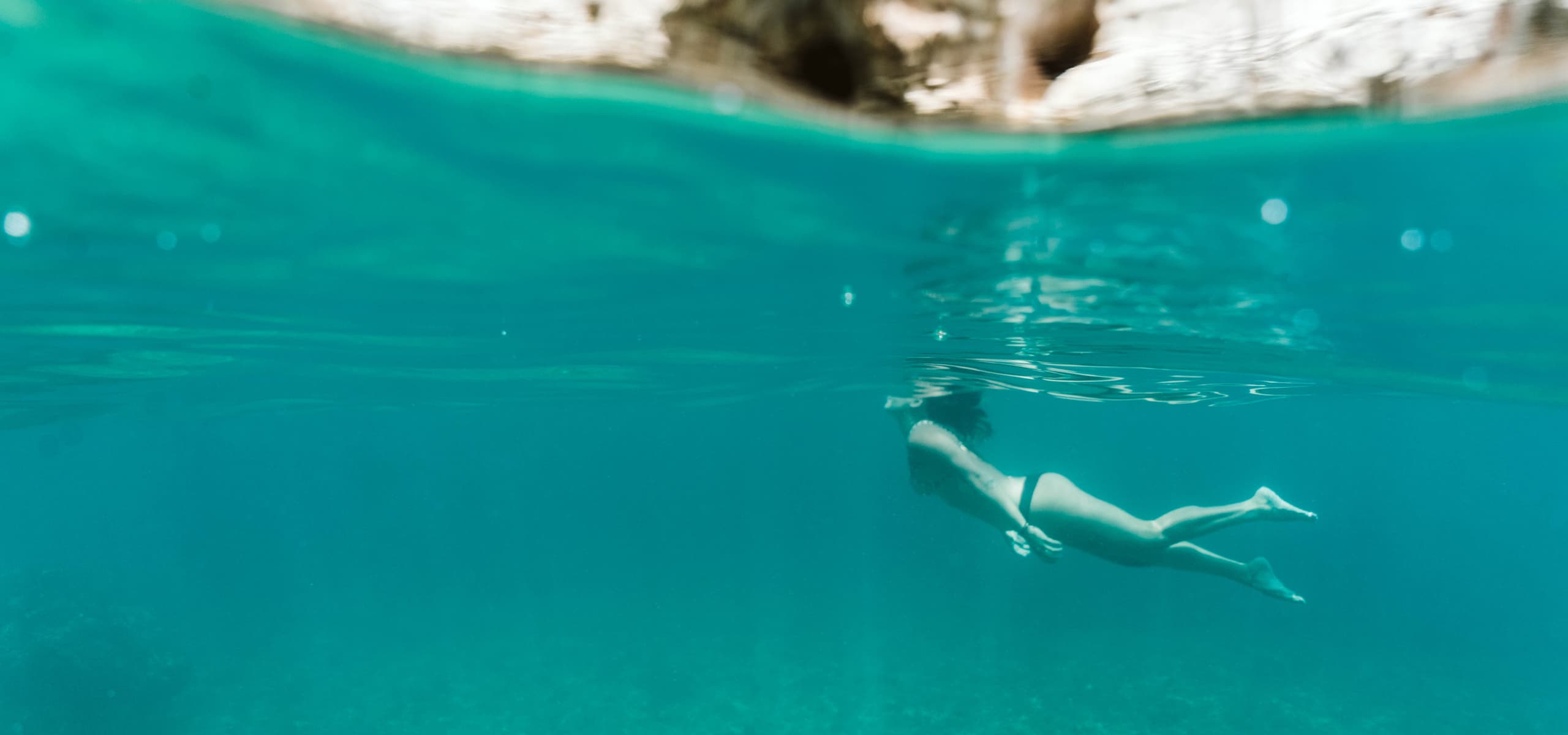 Person swimming underwater in clear turquoise sea near the Mediterranean coast in Alicante, Spain