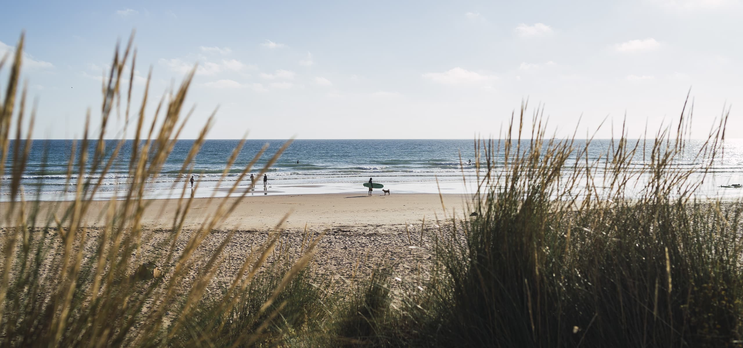 Surfers and beachgoers on a sandy beach with ocean waves in Soulac-sur-Mer, France