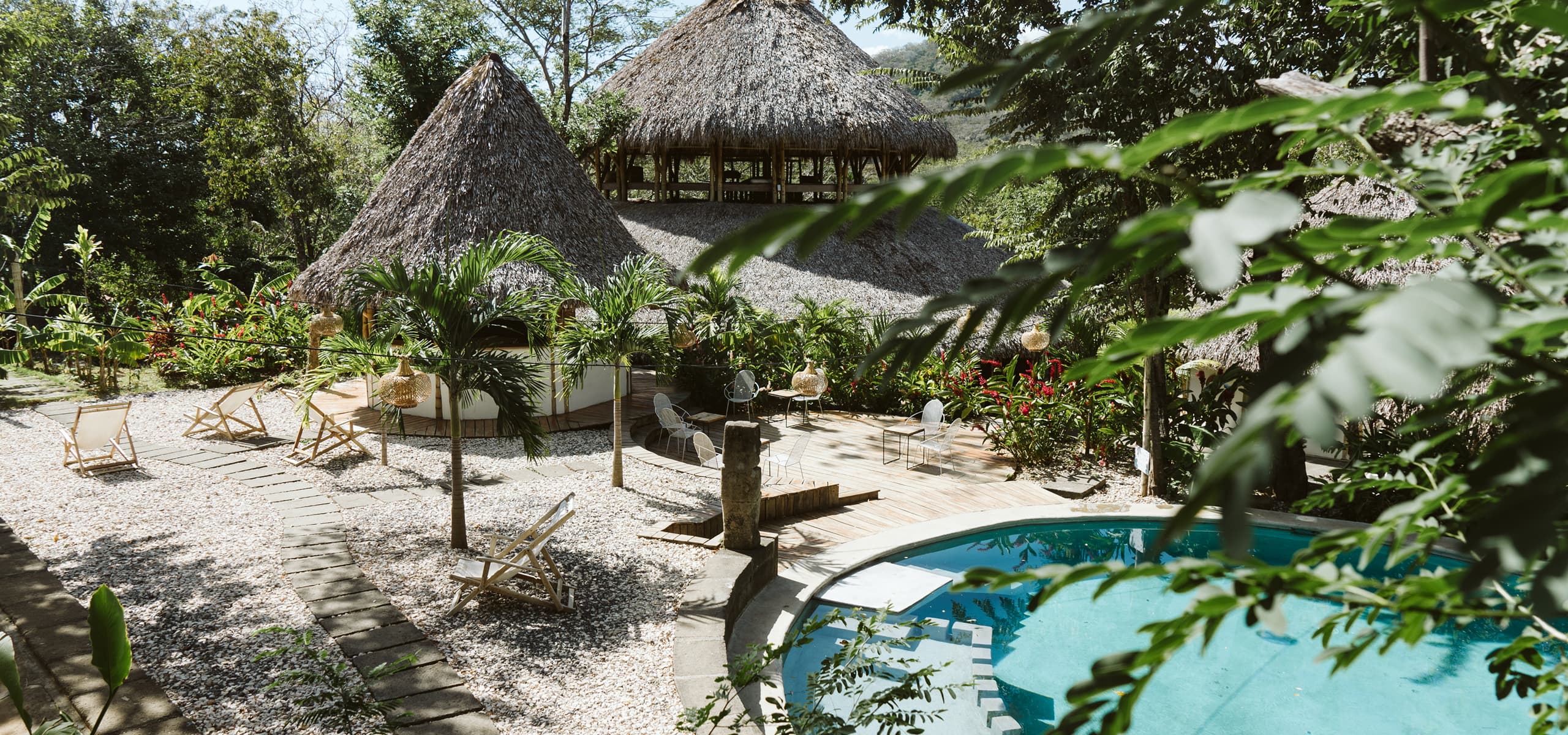 Tropical surf camp with thatched-roof buildings, pool, and outdoor seating in San Juan del Sur, Nicaragua