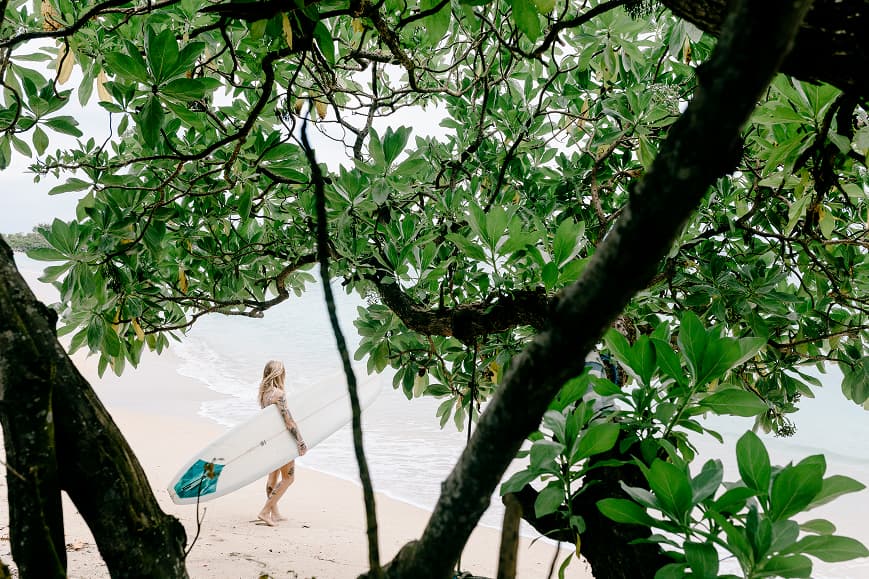 Surfer walking to the beach with a surfboard in Uluwatu Bali
