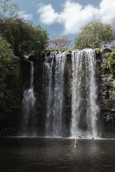 Guest swimming below a waterfall during a Costa Rica nature excursion