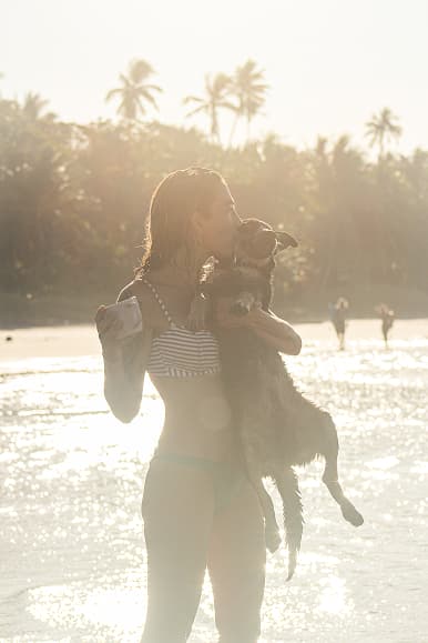 Guest holding a dog on the beach at sunset in Santa Teresa