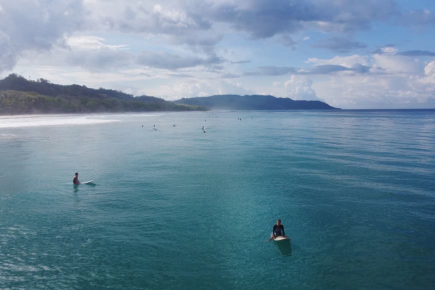 Surfers waiting for waves in the clear water of Playa Hermosa Costa Rica