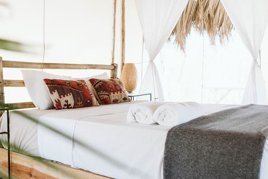 Bright double bed inside a Dreamsea Nicaragua glamping room with bamboo frame and tropical decor