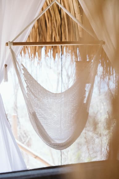 Hanging chair inside a Dreamsea Nicaragua glamping room with thatched roof