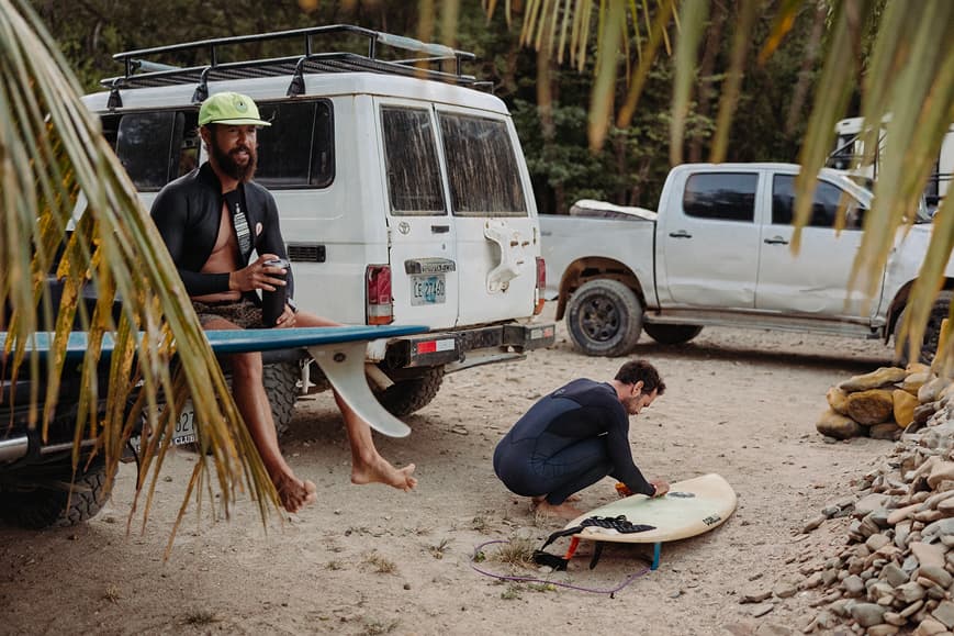 Surfers preparing boards beside beach vehicles before a surf session in Nicaragua
