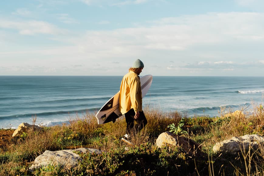 Surfer walking with a surfboard above the Atlantic waves in Sintra
