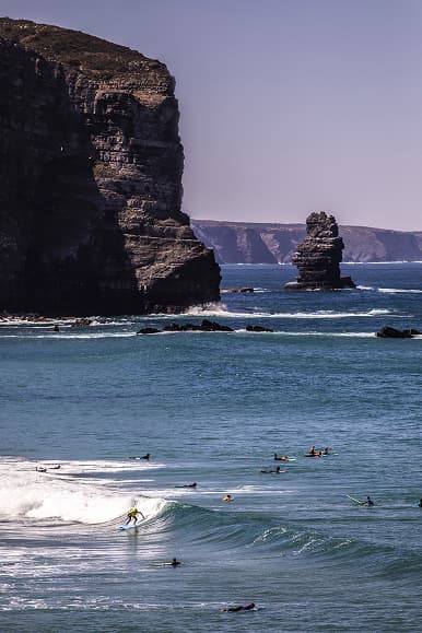 Surfers riding waves below the cliffs on the Sintra coast