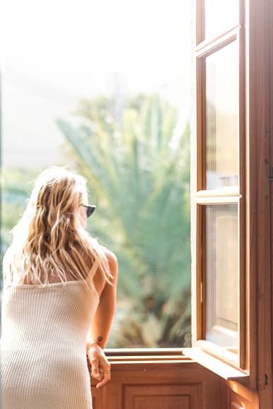 Guest looking out from a room window toward tropical plants in Gran Canaria