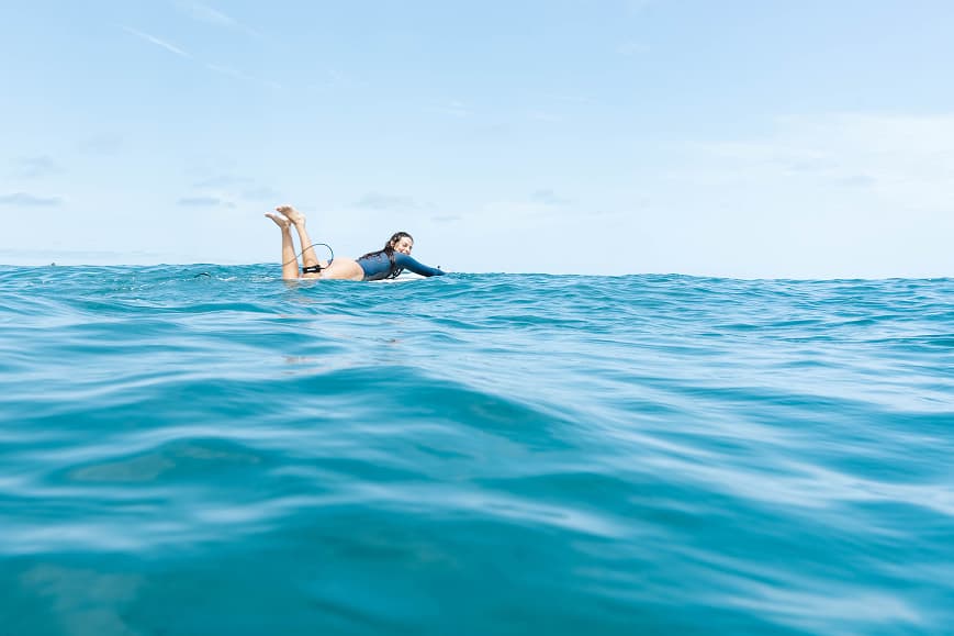 Surfer paddling in clear blue water in Gran Canaria