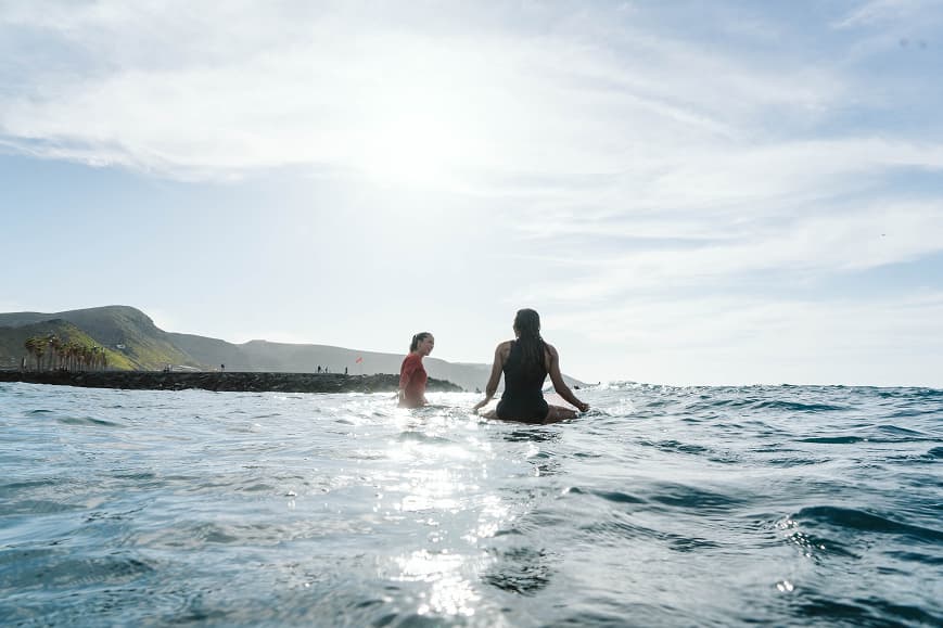 Two surfers sitting on their boards in the ocean near Gran Canaria