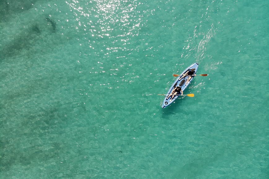 Two guests kayaking in clear turquoise water on the Mediterranean coast