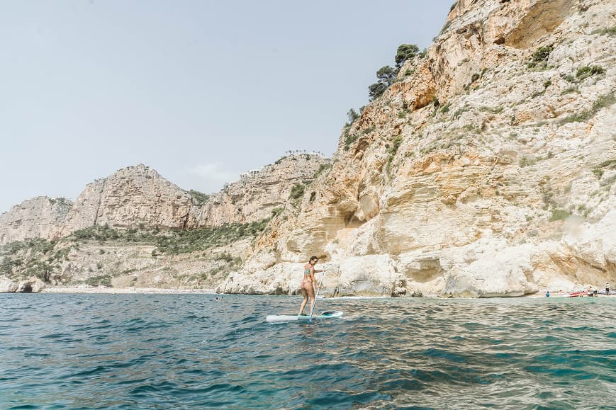 Guest paddleboarding below limestone cliffs on the Costa Blanca