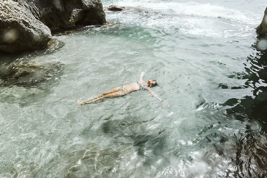 Guest floating in clear water between rocks on the Mediterranean coast