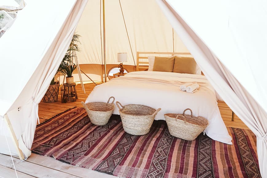 Cozy glamping tent interior at Dreamsea Mediterranean with double bed, woven baskets and patterned rug