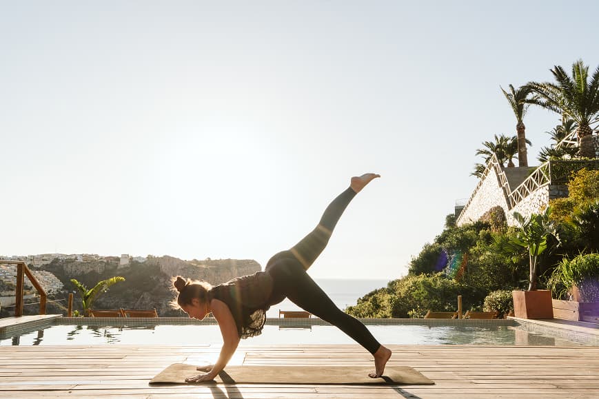 Guest practicing yoga beside the pool with Mediterranean sea views