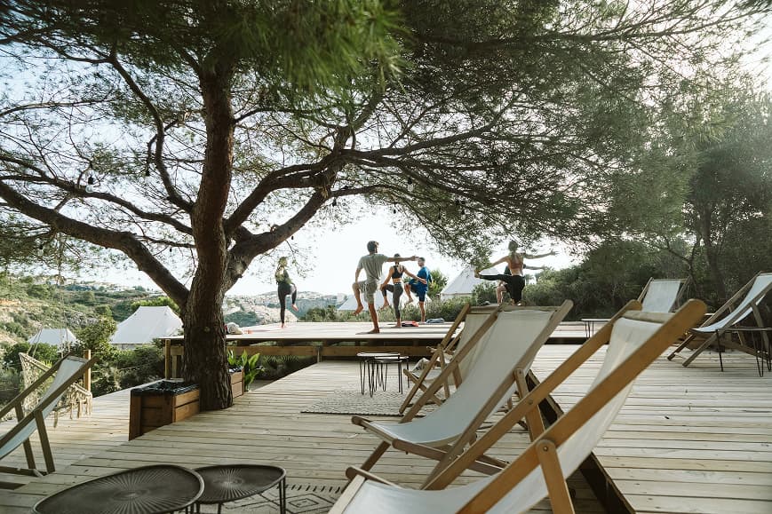 Group yoga class on a wooden deck among trees at Dreamsea Mediterranean